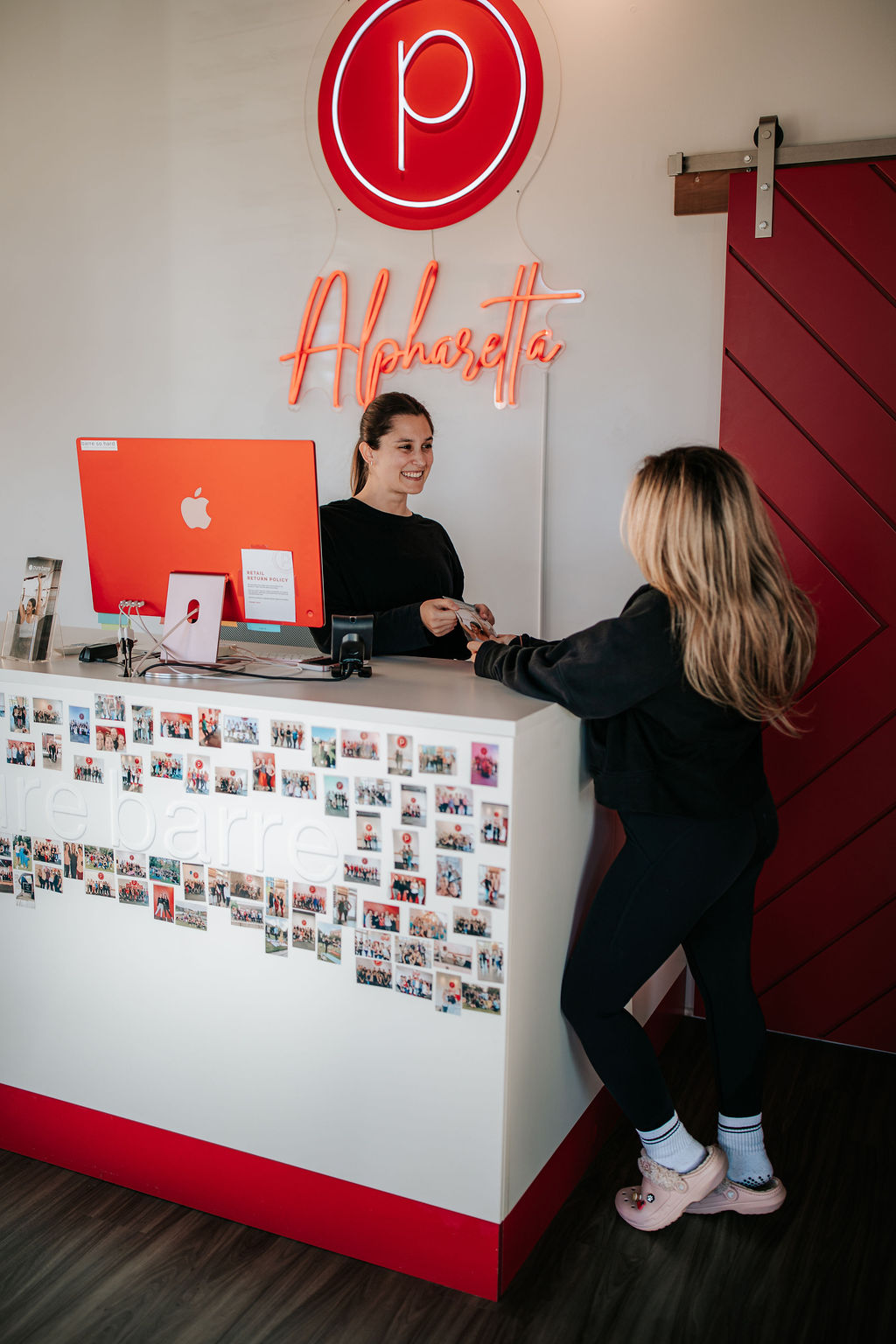 Pure Barre front desk check-in area with staff assisting a client in Atlanta OTP.