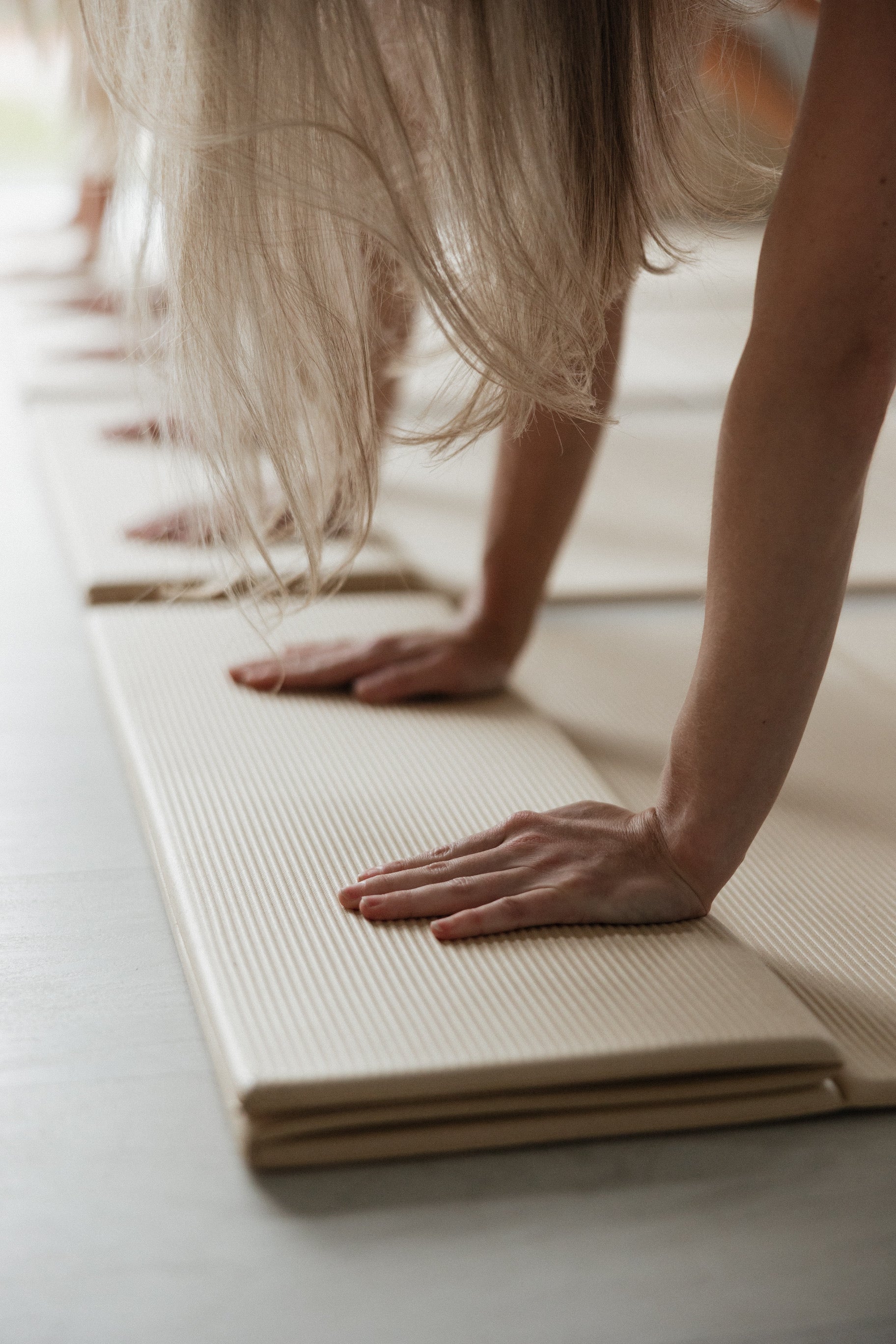 Close-up of hands and bare feet gripping BOJA foldable yoga mat during practice.