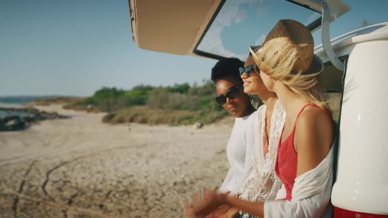 Friends relaxing on a beach beside a vehicle, natural wellness lifestyle scene
