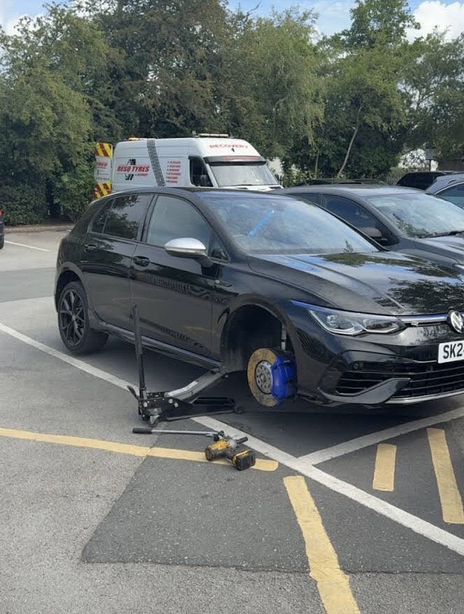 Friendly mechanic smiling while working on a car wheel