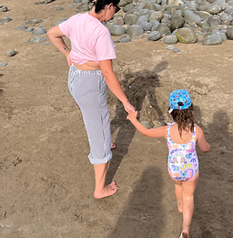Mum and child walking on the beach in Devon, symbolising SEND the Help CIC’s supportive journey with families of send
