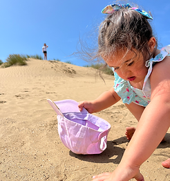 Child building a sandcastle on a Devon beach, symbolising SEND the Help CIC’s support for children with SEND to learn, play,