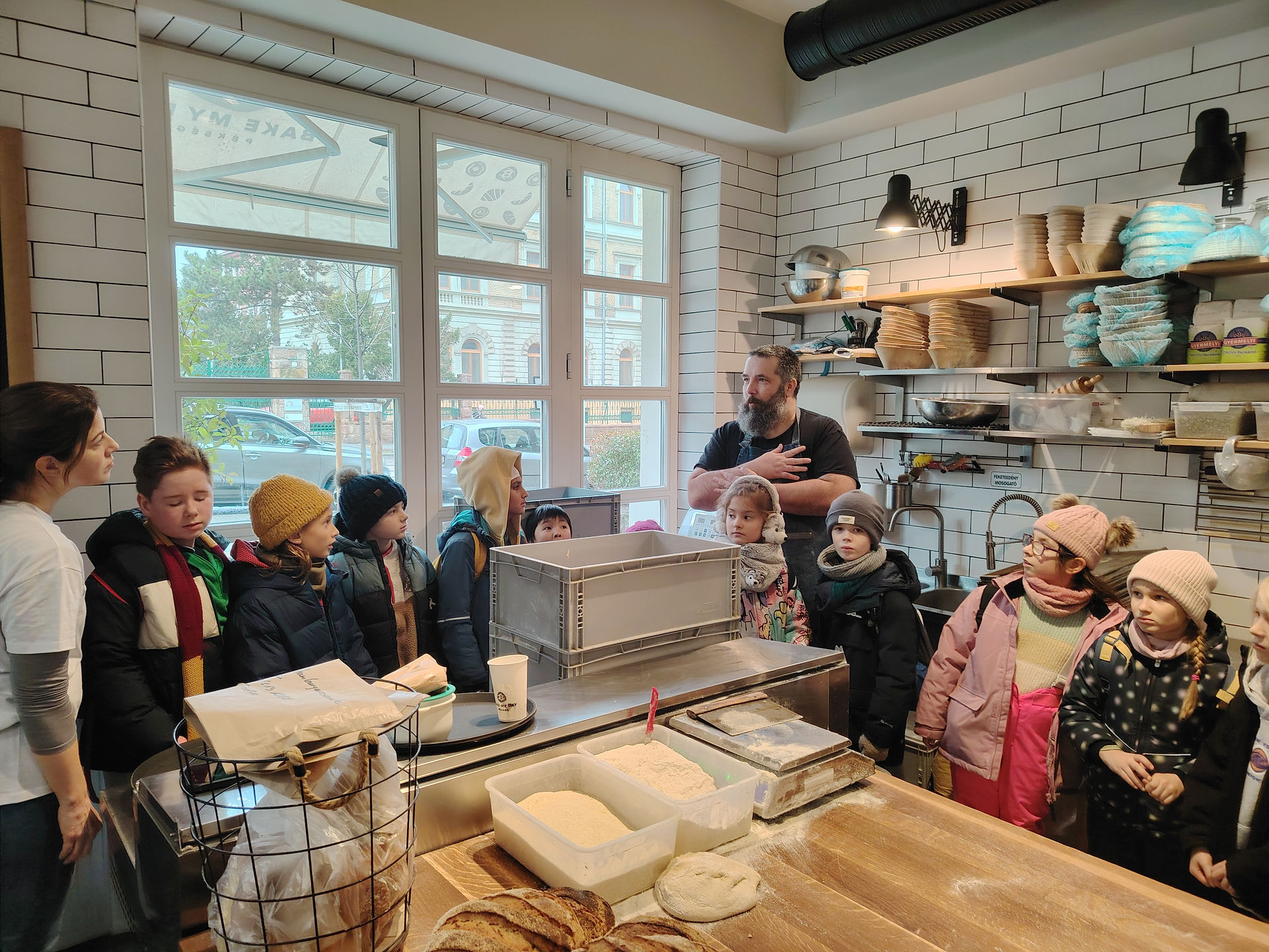 Earth Dragons students seated in the Bake My Day bakery in Budapest, listening to a session about inclusive employment and community during a school excursion