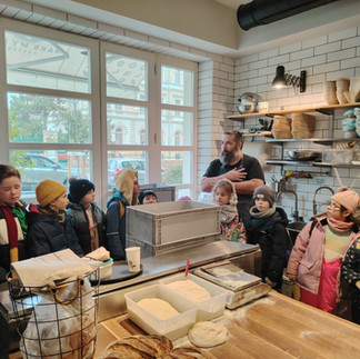Earth Dragons students seated in the Bake My Day bakery in Budapest, listening to a session about inclusive employment and community during a school excursion