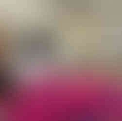 Two REAL School Budapest students sit across a table interviewing a guest from the school's Cultural Compass project, a large red tartan cloth spread between them, in a bright classroom with glazed doors.