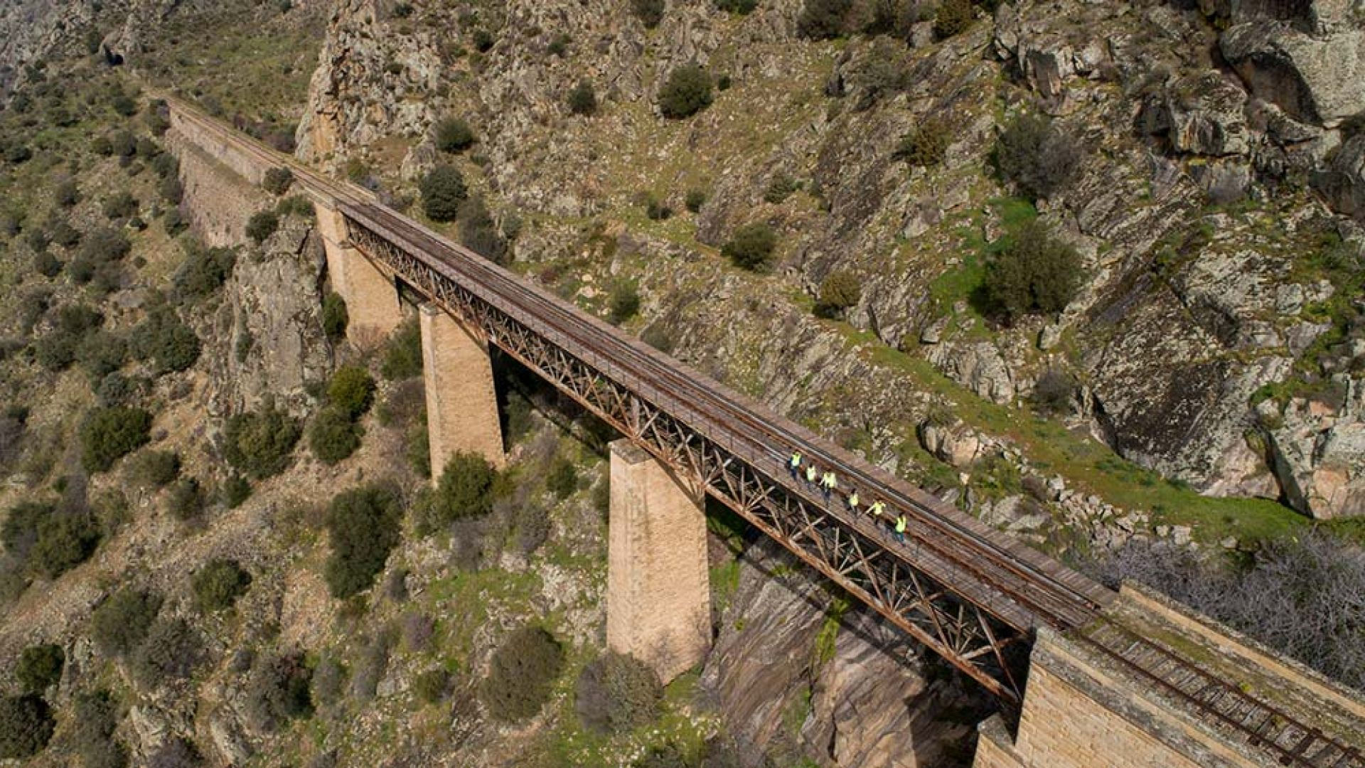 impresionante paisaje y vista aérea de uno de los puentes que conecta dos túneles del camino de hierro. Un puente de dos apoyos centrales y estructura metálica superior.