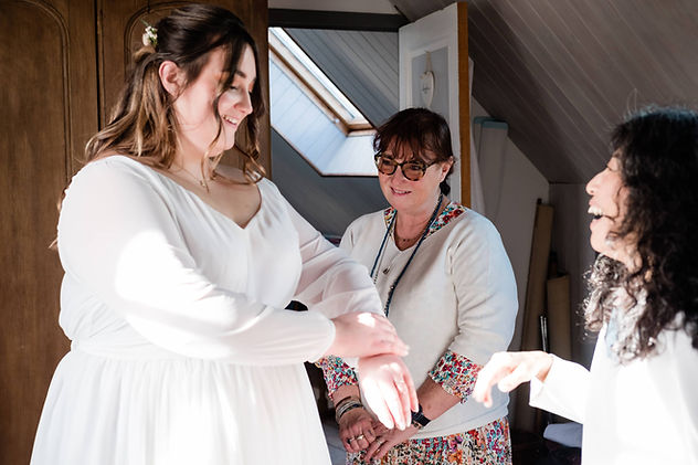 Créatrice habillant une mariée dans sa robe de mariée sur mesure Atelier E le jour du mariage moment d’émotion.