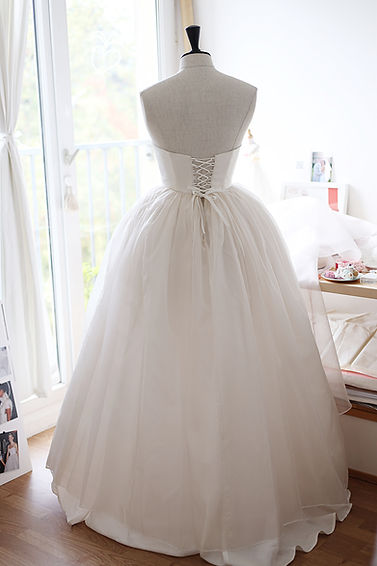 Robe de mariée sur mesure d’Eugene dans l’atelier, le corsage ajusté et la jupe volumineuse en soie superposée, le dos à lacets.