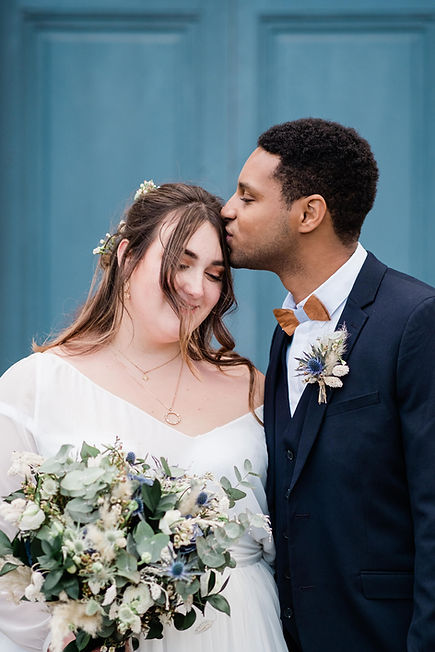 Moment de tendresse entre les mariés après la cérémonie, la mariée portant sa robe sur mesure créée par l'Atelier E.