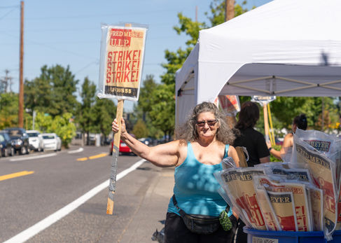 Person holding a "Strike" sign on the street.