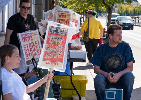 People holding strike signs on a sidewalk.