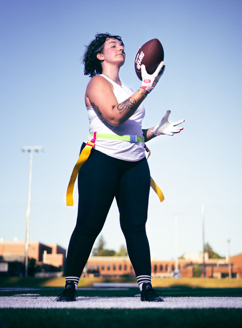 Person holding football, wearing athletic gear outdoors.