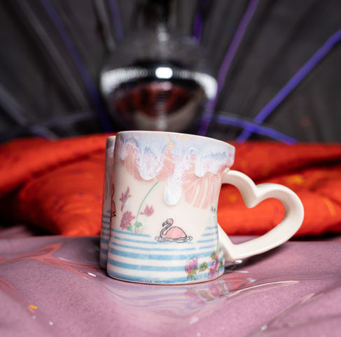 Ceramic mug with heart-shaped handle on colorful background.