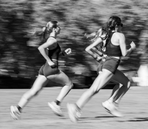 Three women running outdoors in black and white.