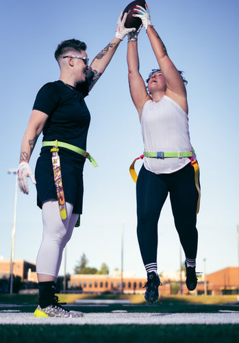 Two people playing flag football outdoors.