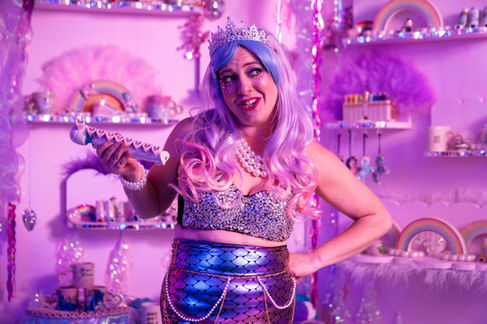 Person in colorful, whimsical costume with pink and purple hues.