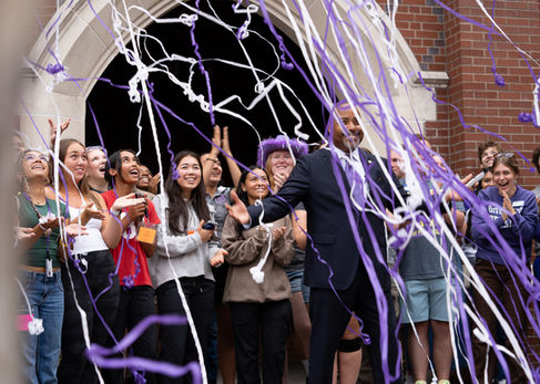 People celebrating with purple and white streamers.