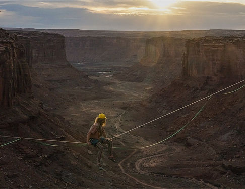 Person sitting on a highline in a canyon.