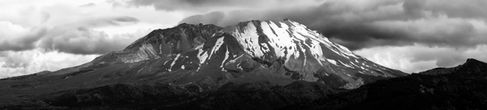 Black and white snowy mountain landscape, cloudy sky.