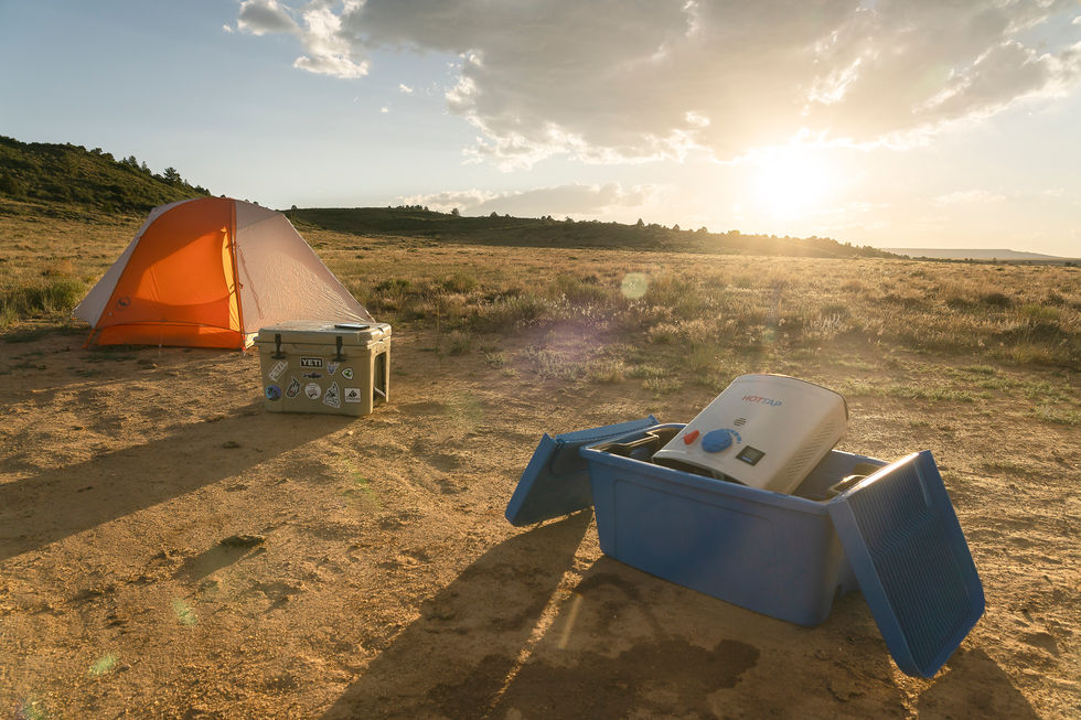 Tent and equipment in a sunny, open landscape.