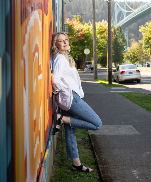 Person leaning against colorful mural on street.