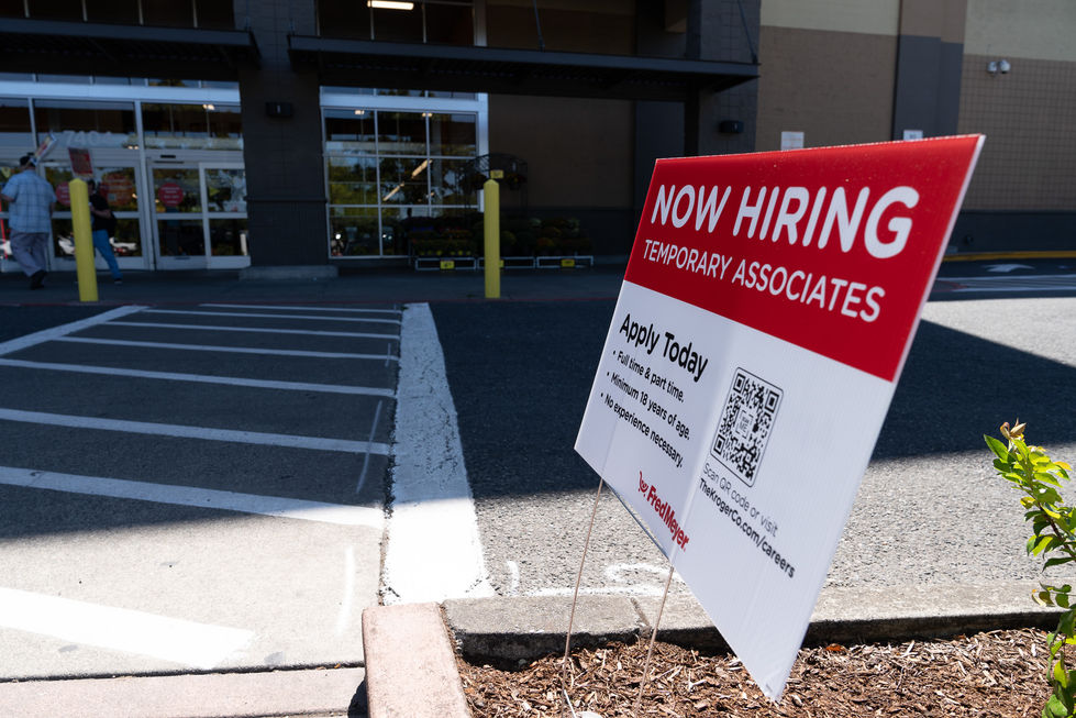 "Now Hiring" sign outside a building entrance.