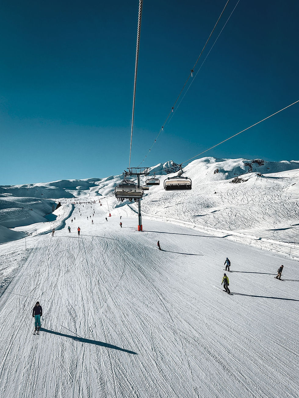 Skiers on wide groomed slopes beneath a chairlift at Les Arcs in the French Alps – peak-week family ski holiday