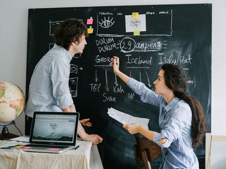 Couple planning their holiday itinerary together with a laptop, globe and chalkboard – why book with an independent travel agent