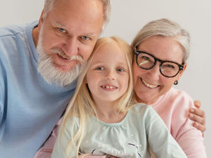 Happy grandparents and their grandchild smiling together indoors, showcasing family love and togetherness.
