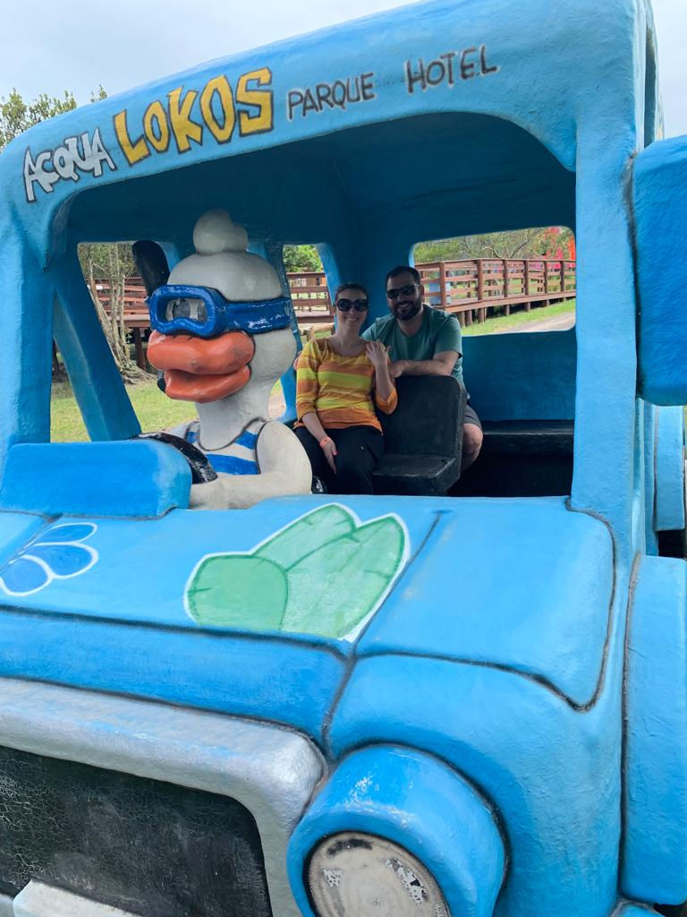 Camila e o namorado sentados num carro temático dirigido por um pato, personagem do Parque Aquático Aqualokos em Capão da Canoa