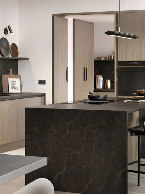 Modern kitchen with Weathered Silver cabinets, black marble-effect island, black appliances, and hidden utility room.