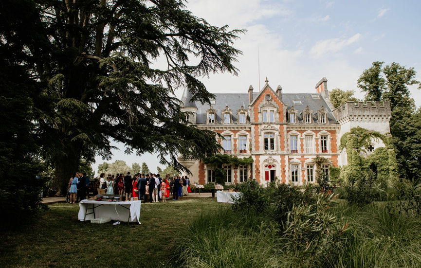Invités réunis devant un domaine pendant une réception de mariage en extérieur.