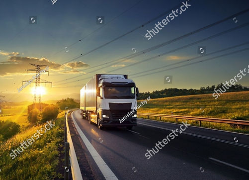 stock-photo-a-truck-driving-through-a-landscape-under-high-voltage-pylons-at-sunset-249616
