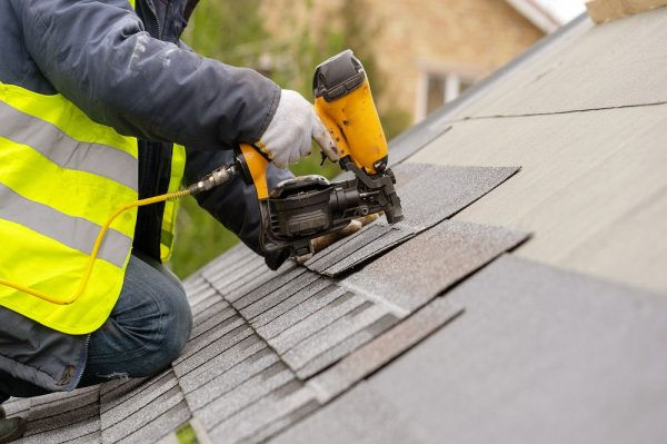 a roofer repairing and replacing shingles