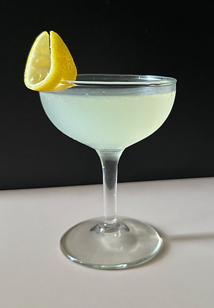 A bright Lemon Drop cocktail in a coupe glass, garnished with a fresh lemon twist against a dark background.