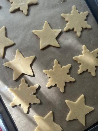 Unbaked snowflake and star sugar cookies on a parchment-lined baking sheet, ready for the oven.