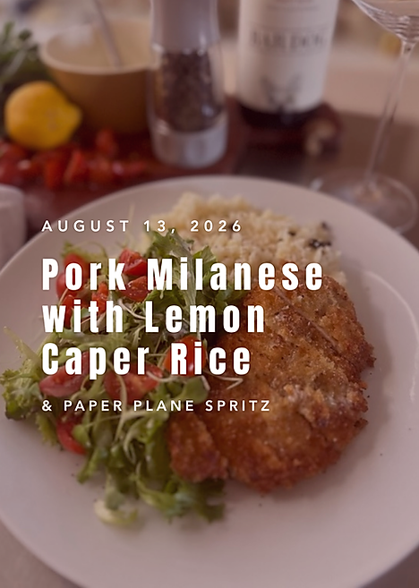 Golden panko crusted pork chop plated with lemon caper parmesan rice and a fresh greens salad, styled for date night with a bottle of wine and lemon in the background.