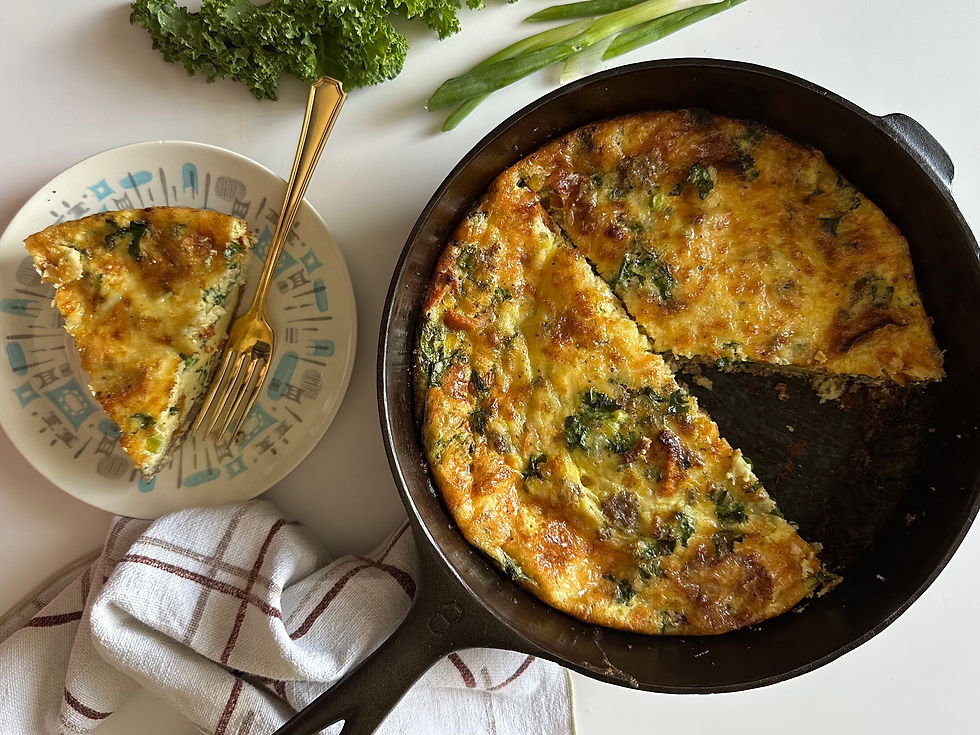 Golden sweet potato, kale, and sausage frittata baked in a cast iron skillet with a slice served on a plate; garnished with fresh kale, green onions, and a kitchen towel.