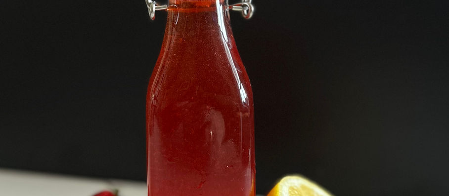 Homemade strawberry shrub bottle on countertop