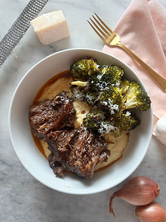 A close-up of a bowl of Japanese curry with tender vegetables and chicken served alongside white rice, set on a patterned tablecloth. A glass of red wine, soft candlelight, and a small potted plant create a cozy, warm atmosphere in the background.