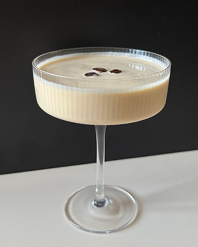 A creamy White Cuban cocktail served in a coupe glass, topped with a single coffee bean garnish.