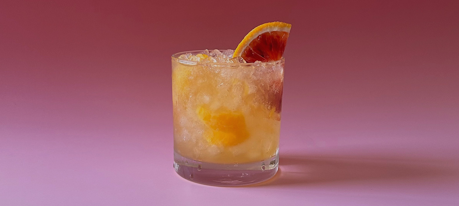 A mandarin margarita on a pink background.