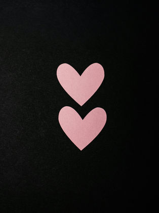 Two pink hearts on a black background, symbolizing love and connection.
