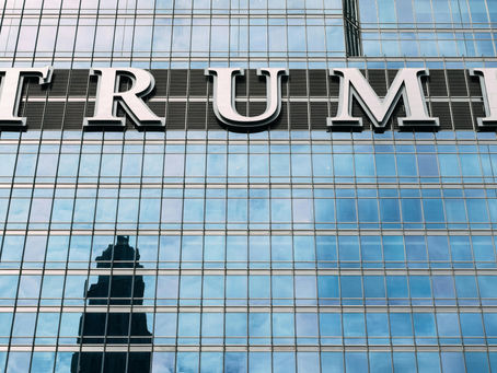 Close-up of the Trump name displayed on the exterior of a modern high-rise building with reflective glass windows, representing commercial real estate, luxury property development, corporate branding, and urban business architecture.