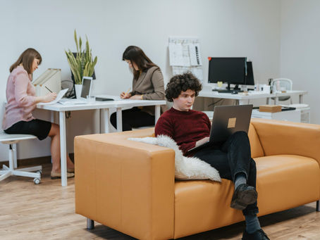 Modern collaborative office workspace with professionals working on laptops and paperwork in a clean contemporary office, representing teamwork, productivity, business operations, remote work, and startup company culture.