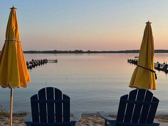 Lakeside seating and umbrellas overlooking Kitchi Lake at Kitchi Landing Resort, offering a peaceful and welcoming Up North cabin experience