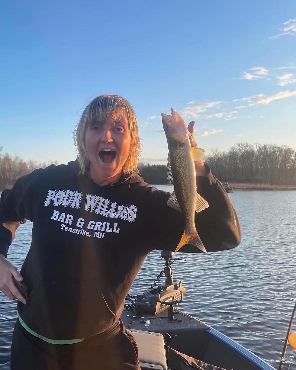Excited angler holding a freshly caught walleye on a fishing boat at Kitchi Landing Resort, with cal