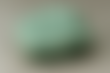 Rough aventurine gemstone with speckled texture on a plain gray background. No text or significant actions. Natural and earthy appearance.