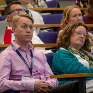 Attendees seated in a lecture theatre listening to a presentation.