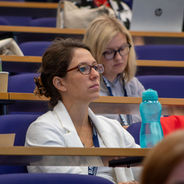 Conference attendee seated in a lecture theatre listening to a presentation.